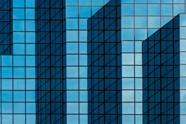 Deep blue geometric glass facade of a modern corporate office tower catching angled daylight