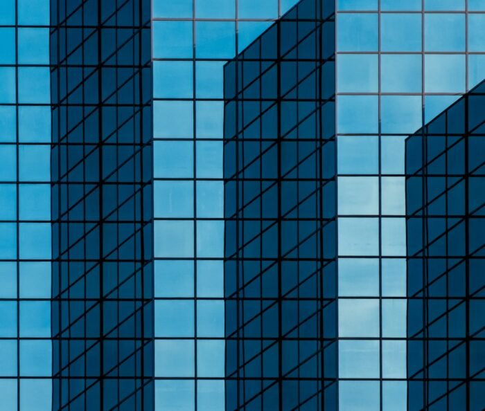 Deep blue geometric glass facade of a modern corporate office tower catching angled daylight