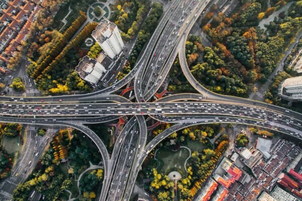 Aerial overhead view of a multi-level concrete highway interchange, lanes converging and weaving together