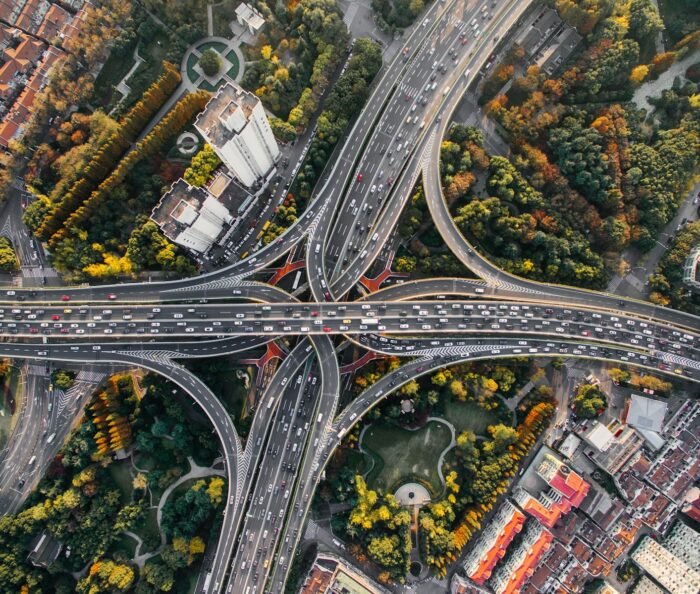 Aerial overhead view of a multi-level concrete highway interchange, lanes converging and weaving together