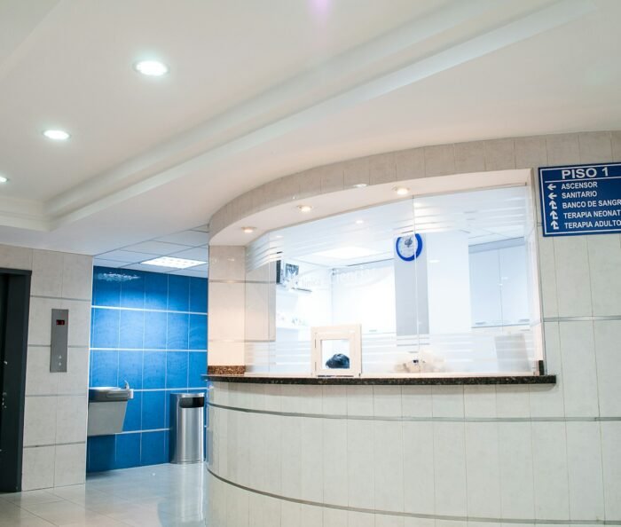 Empty modern clinic reception desk with blue-tile accent and directory signage, no staff present