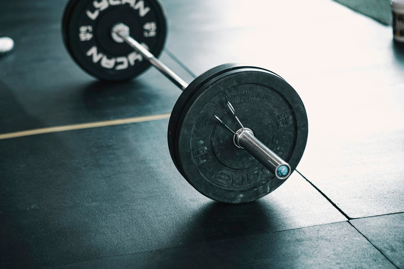 Close-up of a loaded barbell resting on the rubber floor of a strength and conditioning gym