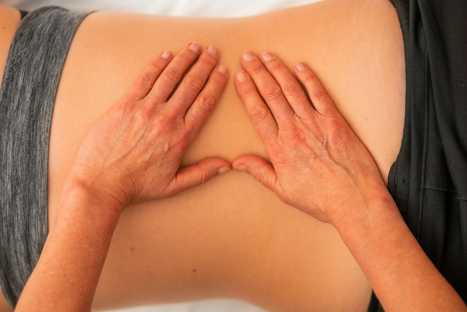 Close-up of a therapist's hands performing manual treatment on a patient's back
