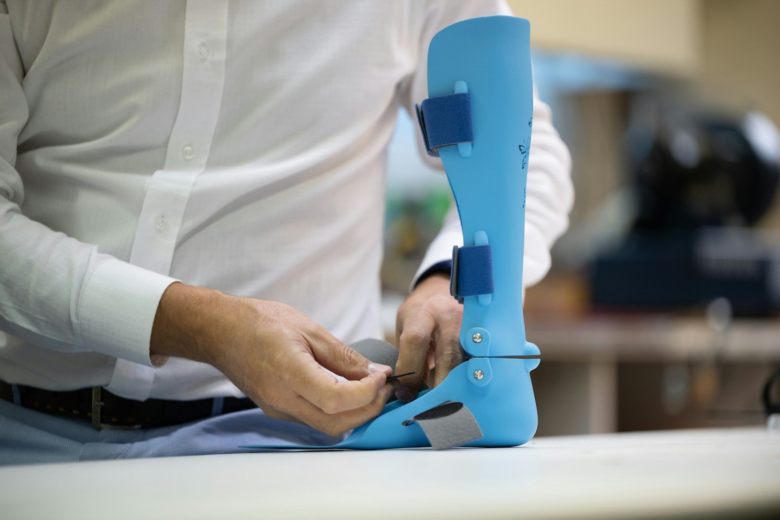Clinician's hands adjusting a custom ankle-foot orthotic brace on a workbench