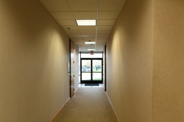 Empty, quiet office corridor with a closed door, evoking the isolation of a workplace psychological injury.