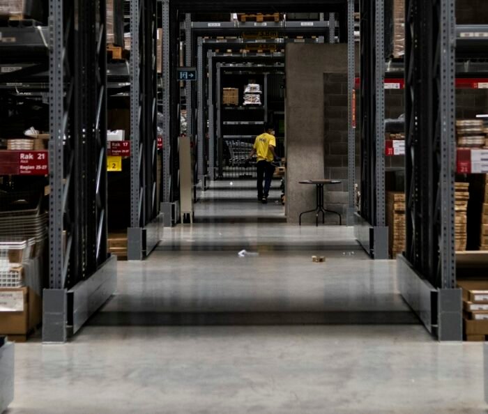Warehouse aisle stacked with boxes, representing the physical roles needing a pre-employment medical assessment.