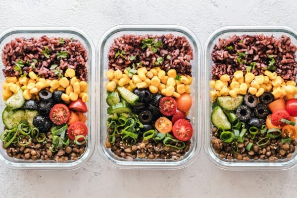 Three healthy meal-prep containers of rice, vegetables and lentils, the kind of meal an NDIS dietitian plans.