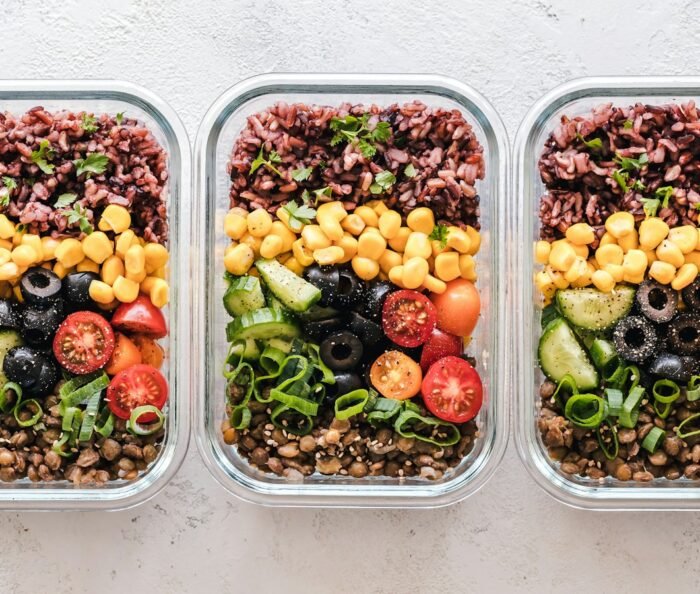 Three healthy meal-prep containers of rice, vegetables and lentils, the kind of meal an NDIS dietitian plans.